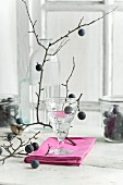 Schlehdornschnaps in einem Glas, Schlehdornfrüchte im Vorratsglas und Schlehenzweig auf Küchentisch