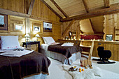 Twin beds and cubby bed, furs and toys on floor in wood-clad chalet