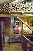 Treppenabsatz mit Holzlager in rustikalem Chalet, Blick ins Schlafzimmer
