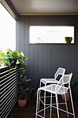 White metal bar stool on balcony with plants