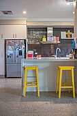 Moderne Küche mit gelben Hockern und Tafel an der Wand