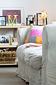 Scatter cushions on loose-covered sofa in front of shelves