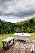 Vintage Badewanne mit Klauenfüßen und Holzbank auf Holzdeck vor Hügellandschaft, Reserva do Ibitipoca, Brasilien