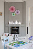 Paper rosettes on grey wall above log burner in child's bedroom