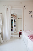 Doorway screened by curtain between rooms decorated entirely in white