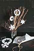 Christmas decorations hand-made from white clay arranged on branches against black background