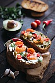 Healthy sandwiches with cheese cream, salmon and vegetables on wooden board