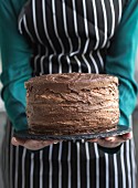 Homemade chocolate cake in baker hands