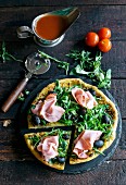 Served pizza topped with ham and rocket