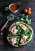 Pizza mit Schinken, Oliven und Rucola, angeschnitten