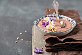 Chocolate pudding with chopped hazelnuts and edible flowers (daisies, violets)
