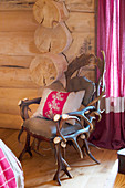 Quaint armchair made from antlers and embroidered cushion in log cabin