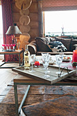 Bottle of wine and glasses on tray on coffee table in log cabin
