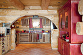 Rustic kitchen with terracotta floor tiles in log cabin