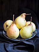 A plate of fresh pears on a dark moody background