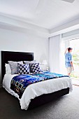 Man is standing at the patio door in the bedroom with a black bed