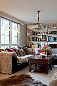 Sofa below window and bookshelves in cosy living room