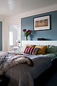 Fur blanket on bed against blue wall panel in bedroom