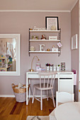 Shelves on wall above desk in child's bedroom in pastel shades