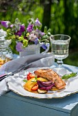 Salmon with a honey and lemon glaze, with summer vegetables on a table outdoors