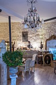 Antiques, crystal chandelier, chest of drawers and gilt-framed mirror on stone wall