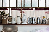 Arrangement of vintage objects on wall-mounted shelves against hand-made curtains embroidered with initials