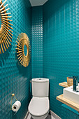 Turquoise wall tiles and sunburst mirrors in guest toilet