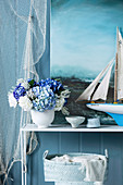 Bouquet of hydrangeas, model of a sailing ship and paintings with a sea motif as a maritime decoration