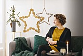 Woman sitting on sofa in front of Christmas stars hand-made from natural materials