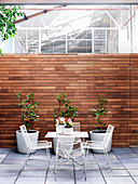 Tisch mit Stühlen und Pflanzengefäße im Innenhof mit Sichtschutz aus Holz
