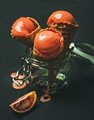 Refreshing summer blood orange ice cream or sorbet scoops in sweet waffle cones in glass jar