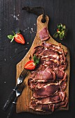 Turkish pastirma with strawberry, highly seasoned, air-dried cured beef meat cut in slices on wooden board