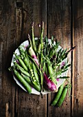 Frisches grünes Gemüse auf Teller und Holztisch (Aufsicht)
