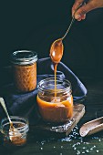 Salted caramel sauce dripping from a spoon into a glass