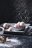 Dusting icing sugar over Castagnole (fried pastries, Italy)