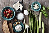 Ingredients for a strawberry salad with asparagus, bread, spring onions and feta