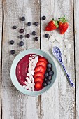 A smoothie bowl with strawberries, blueberries and coconut chips