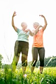 Two women exercising with arms raised
