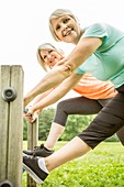 Two women smiling towards camera with legs on railings