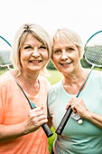 Two women holding badminton rackets, smiling