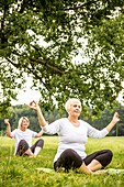 Two women doing yoga in field