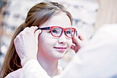 Optometrist trying glasses on girl