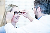 Optometrist trying glasses on woman
