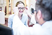 Optometrist trying glasses on woman