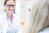 Optometrist trying glasses on woman