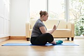 Woman sitting on floor using digital tablet