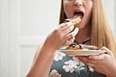 Young woman eating chocolate eclair