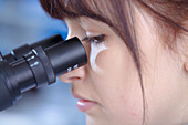 Female medical student using microscope