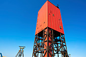 Red drilling rig against a clear blue sky