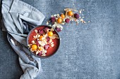 A smoothie bowl with almonds, physalis, and raspberries
